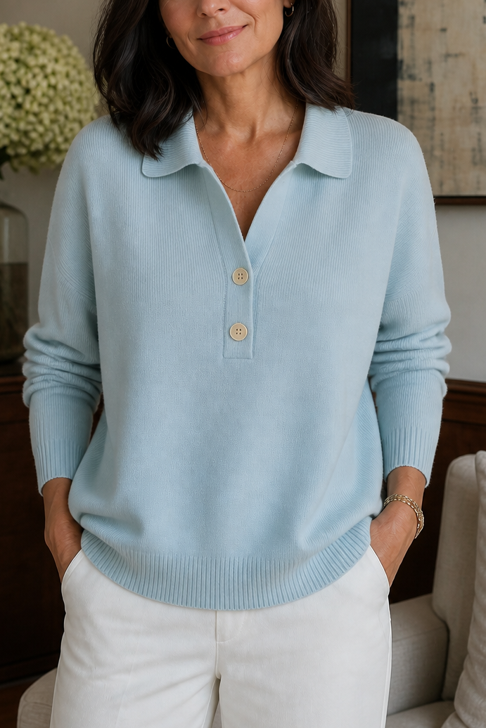 Light blue polo collar sweater with two wooden buttons and ribbed cuffs, worn with white trousers