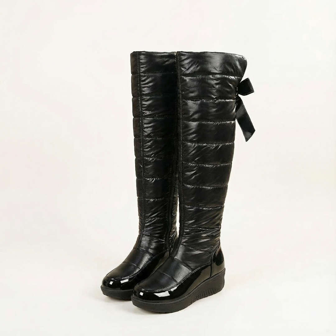 Pair of black quilted over the knee snow boots with bow backs