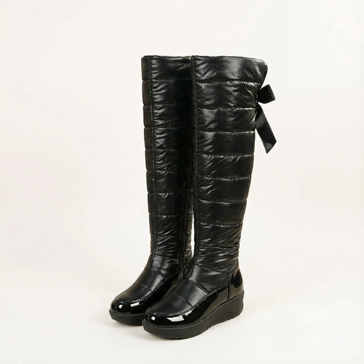 Pair of black quilted over the knee snow boots with bow backs