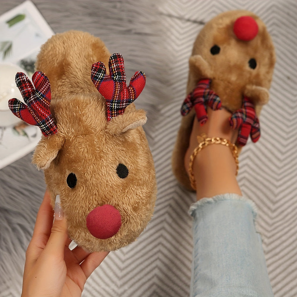 Hand holding a tan fluffy reindeer slipper with a red pom nose