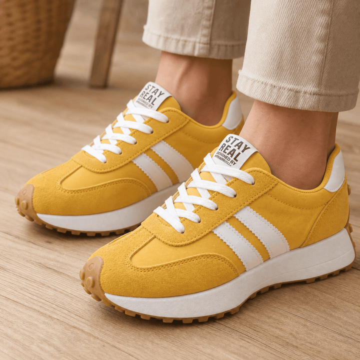 Yellow suede sneakers with white side stripes, white laces and a gum sole