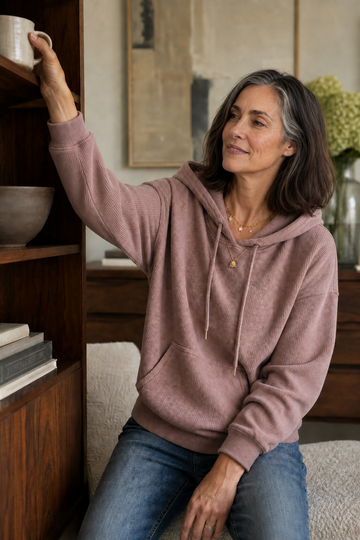 Woman reaching to a shelf in a mauve ribbed corduroy look hoodie