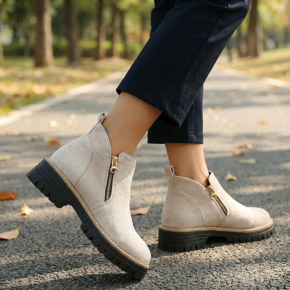 Cream suede chelsea boots worn with navy trousers outdoors