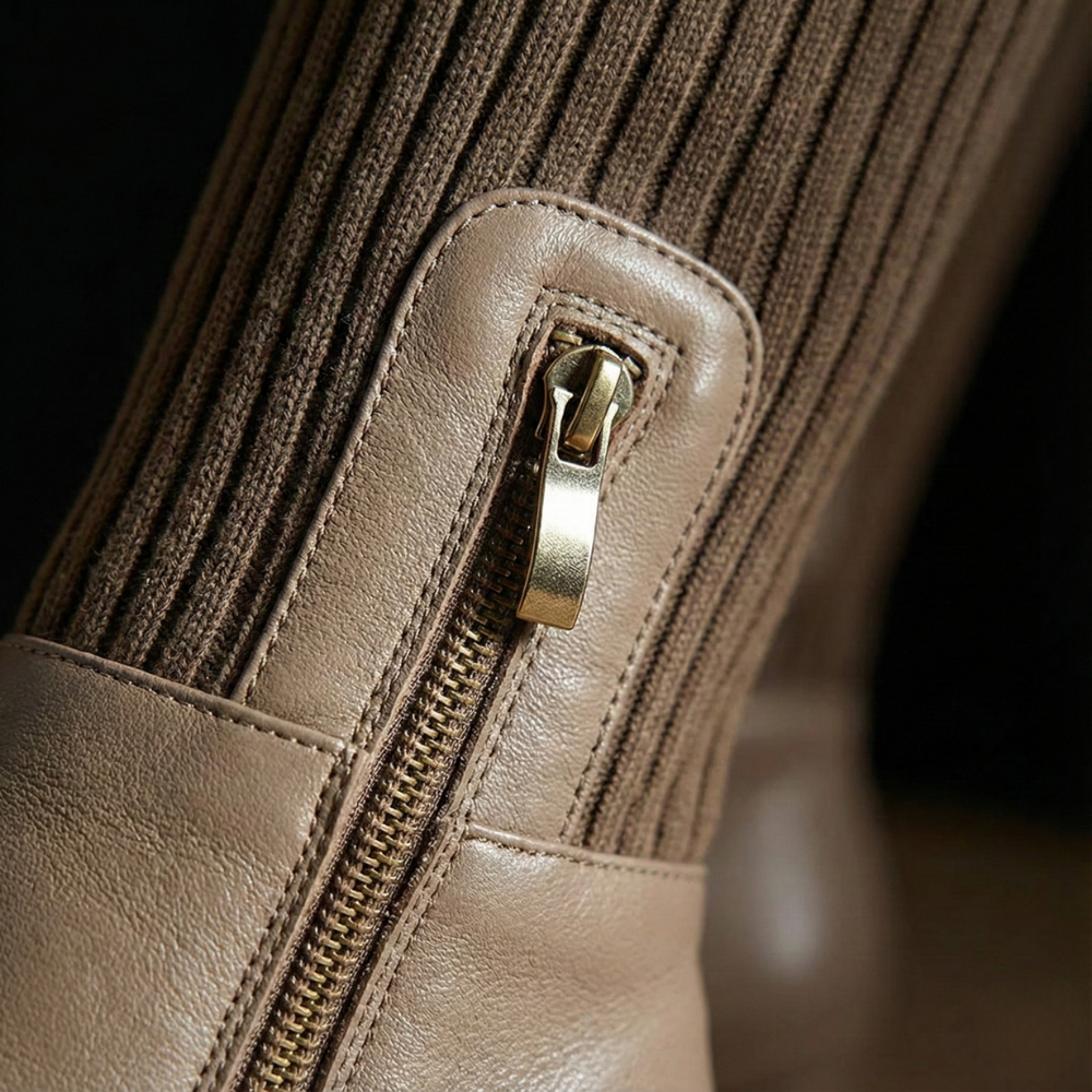Close-up of the gold side zip on a taupe knee high boot with a ribbed knit shaft