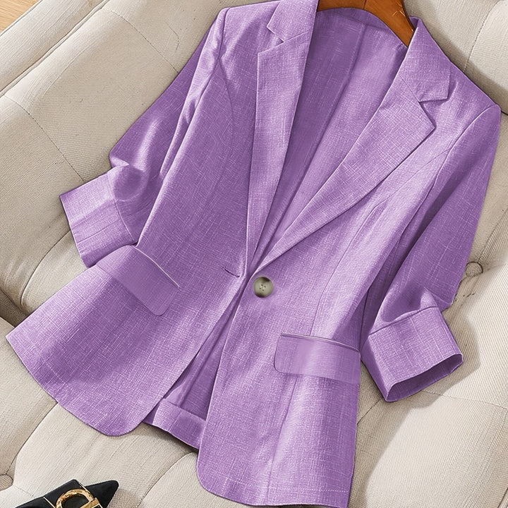 Lilac cropped blazer with rolled cuffs laid on a cream sofa