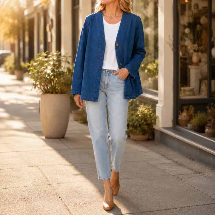 Woman on a pavement in a collarless denim look jacket and jeans