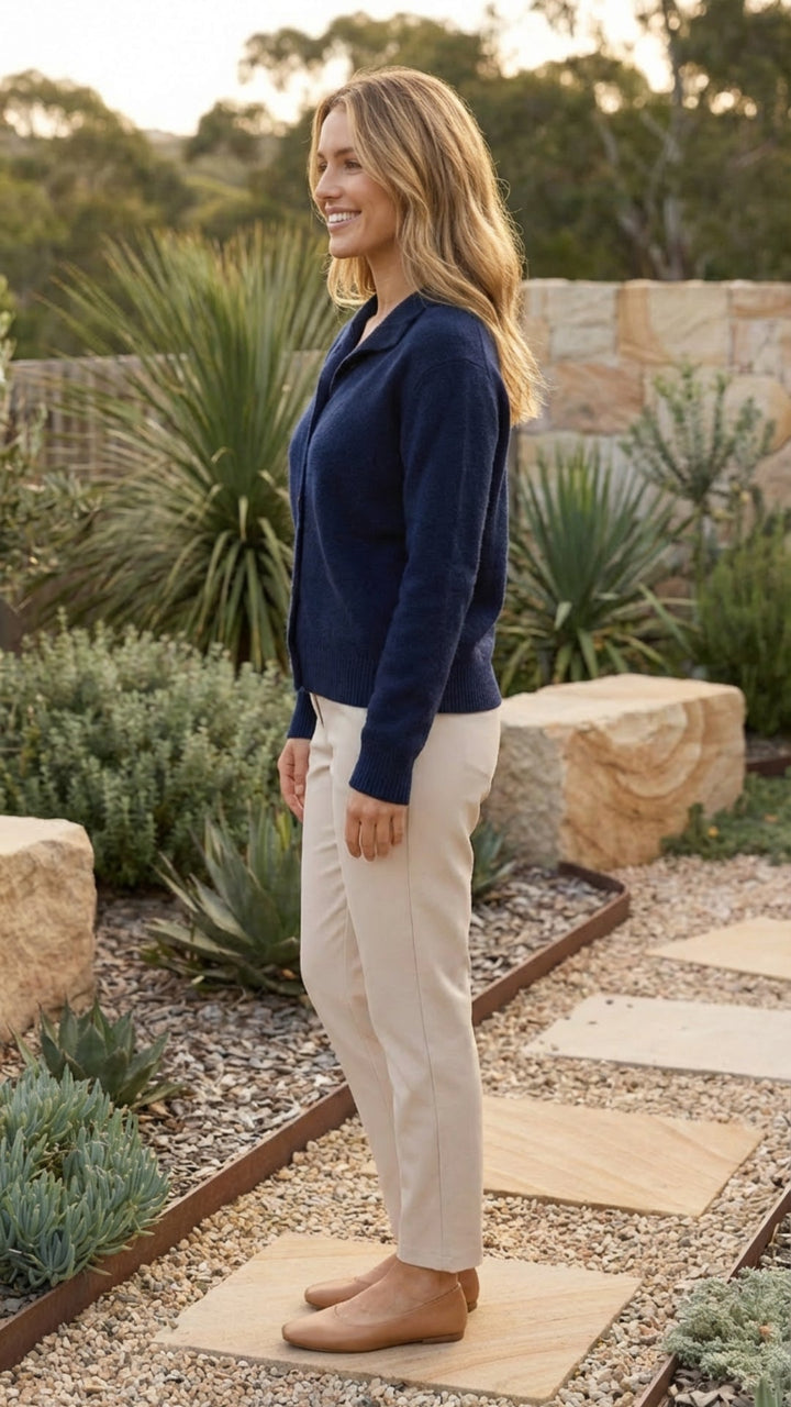 Navy knit button front cardigan with collar, side view worn with cream trousers