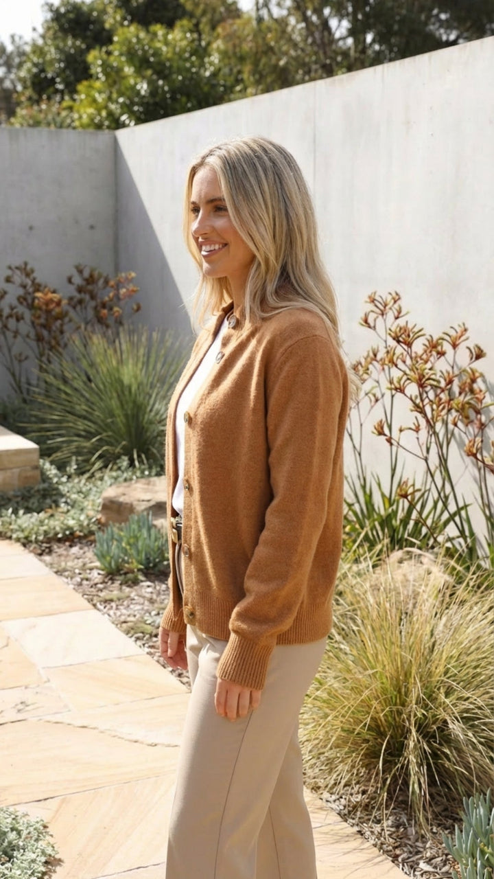 Side view of a camel button front knit cardigan worn over a white tee