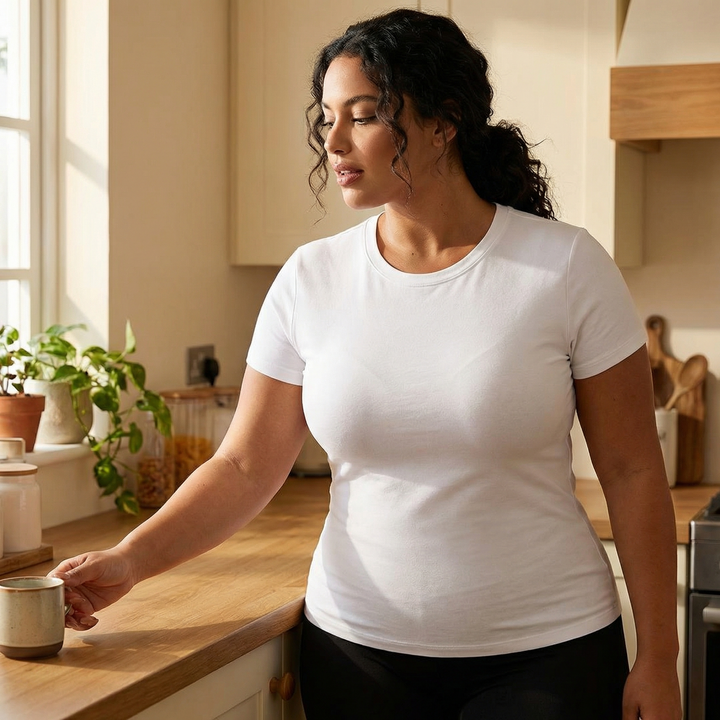 Woman in a white tee reaching for a mug in a kitchen