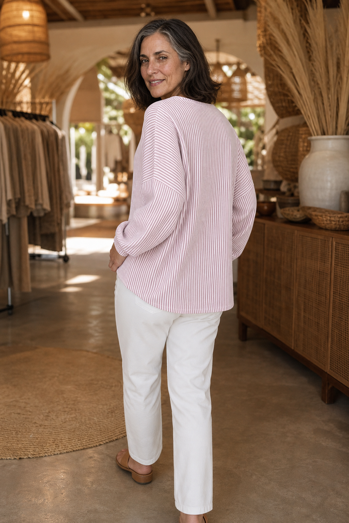 Back view of a pink striped quarter zip top with white trousers