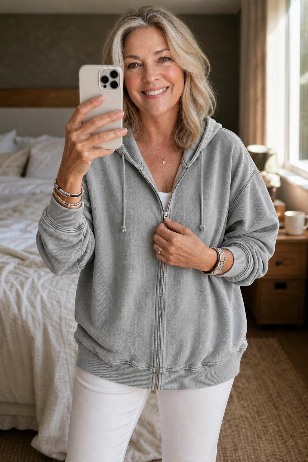 Woman in a bedroom wearing a grey washed zip up hoodie