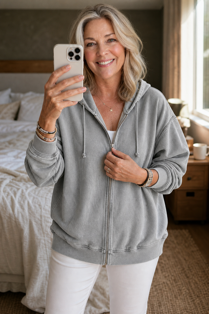 Woman in a bedroom wearing a grey washed zip up hoodie