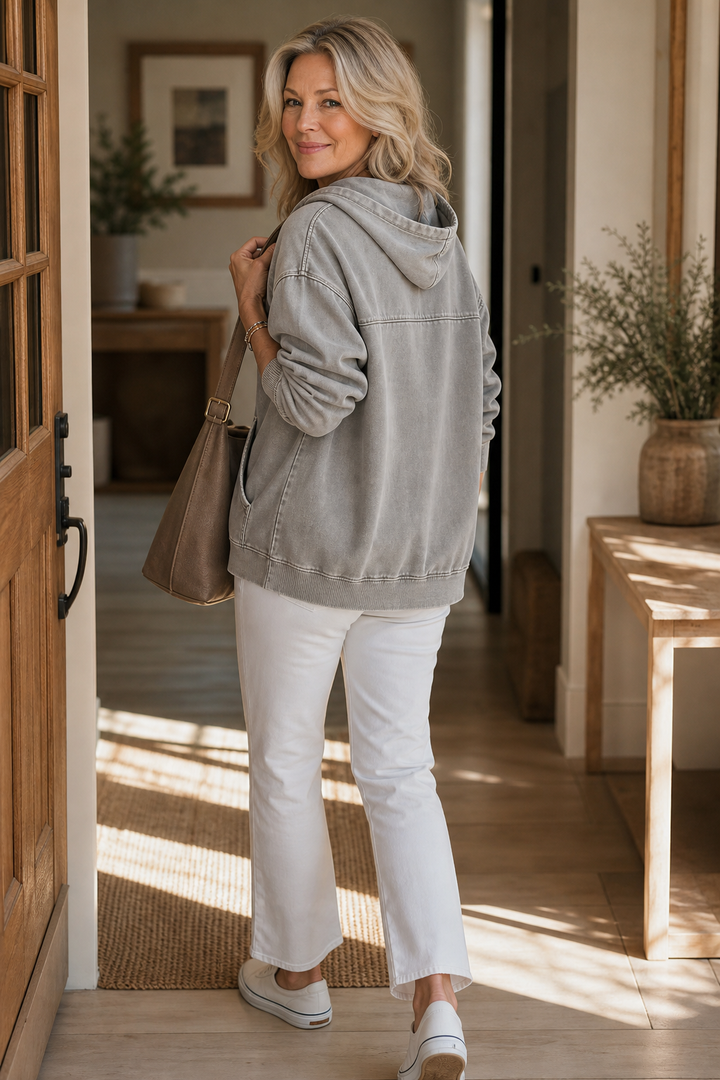Grey washed zip up hoodie with a shoulder bag in a hallway