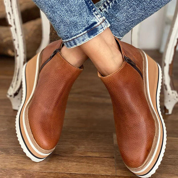 Tan leather ankle boots with a striped wedge sole worn with jeans