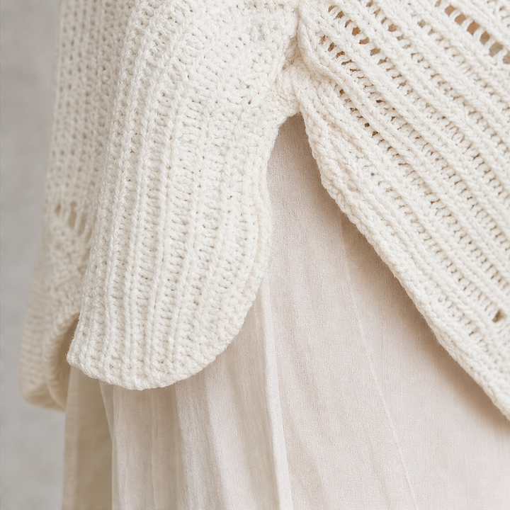 Scalloped side split hem detail on a cream openwork sweater