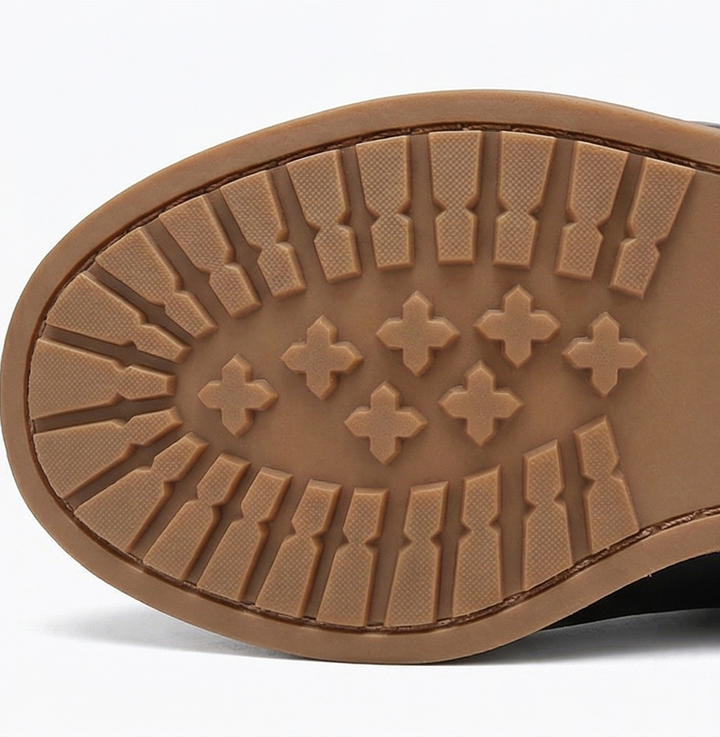 Treaded tan rubber outsole of a black lace up boot